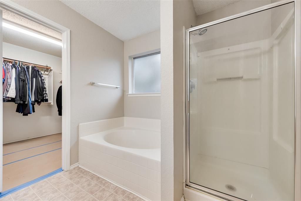617 Madeline Court Azle, TX 76020 - Photo 13 of 20 Full bathroom featuring a spacious closet, a textured ceiling, a shower stall, and a garden tub