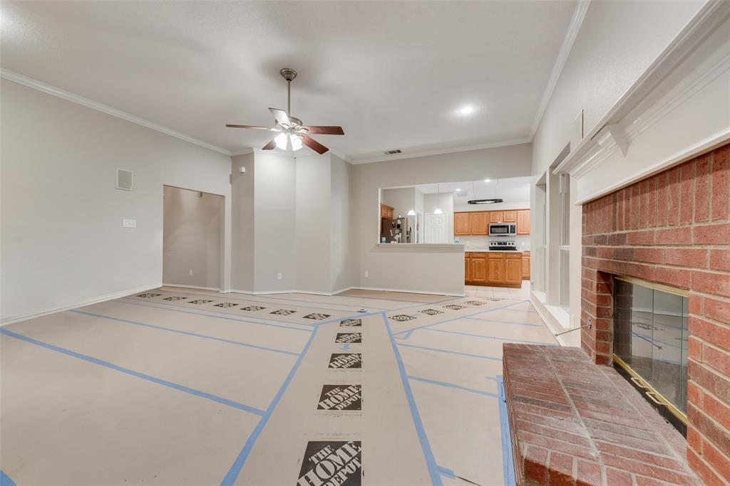 617 Madeline Court Azle, TX 76020 - Photo 5 of 20 Unfurnished living room featuring crown molding, a ceiling fan, and a fireplace