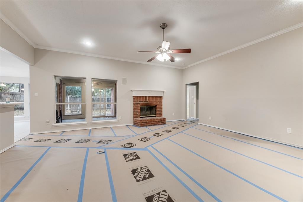 617 Madeline Court Azle, TX 76020 - Photo 6 of 20 Unfurnished living room with a brick fireplace, ceiling fan, and ornamental molding