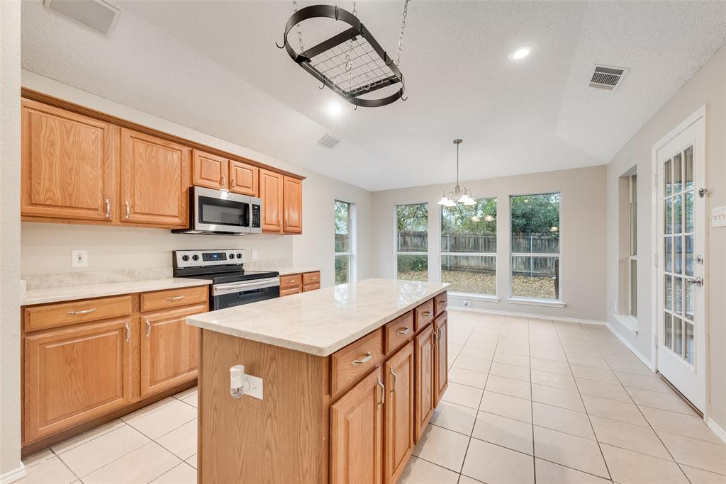 617 Madeline Court Azle, TX 76020 - Photo 8 of 20 Kitchen featuring stainless steel appliances, pendant lighting, light tile patterned floors, a chandelier, and a kitchen island