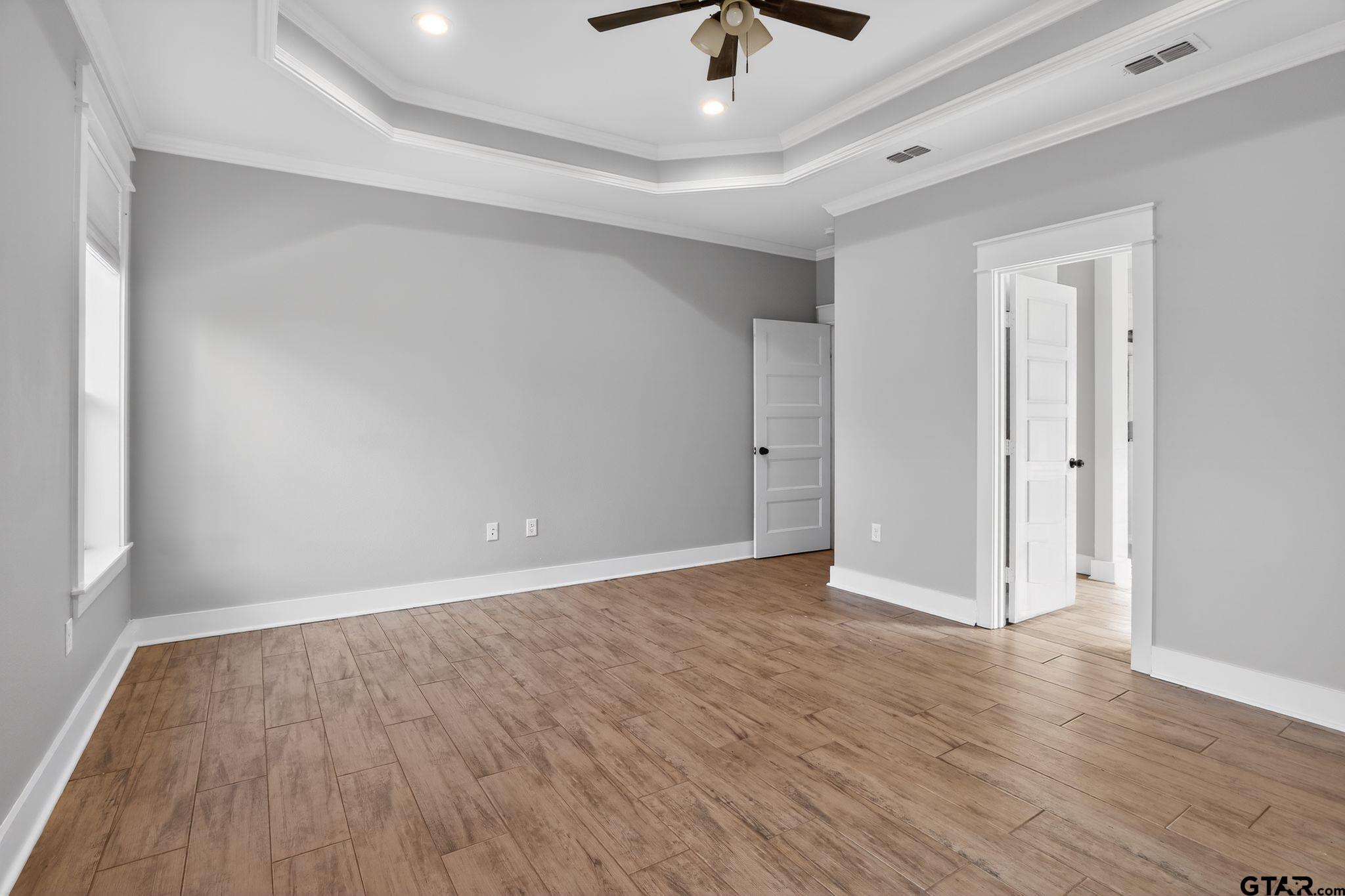 7600 County Road 210 Tyler, TX 75702 - Photo 18 of 30 an empty room with wooden floor and ceiling fan