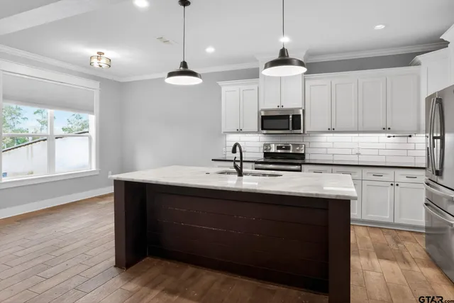 a kitchen with stainless steel appliances granite countertop a sink a stove a refrigerator and cabinets