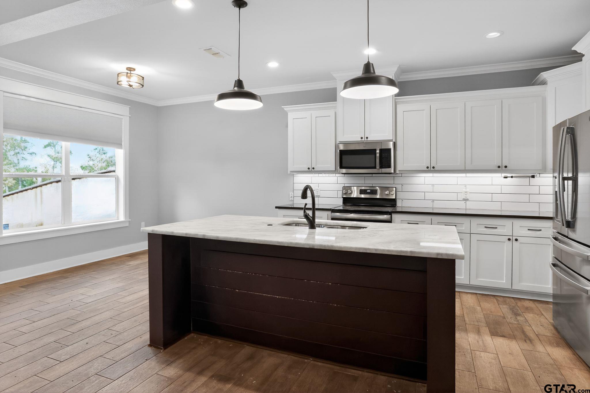 7600 County Road 210 Tyler, TX 75702 - Photo 10 of 30 a kitchen with kitchen island granite countertop a sink a counter space appliances and cabinets