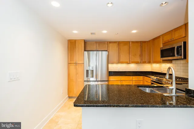 a kitchen with stainless steel appliances granite countertop a sink a stove and a refrigerator with wooden floor