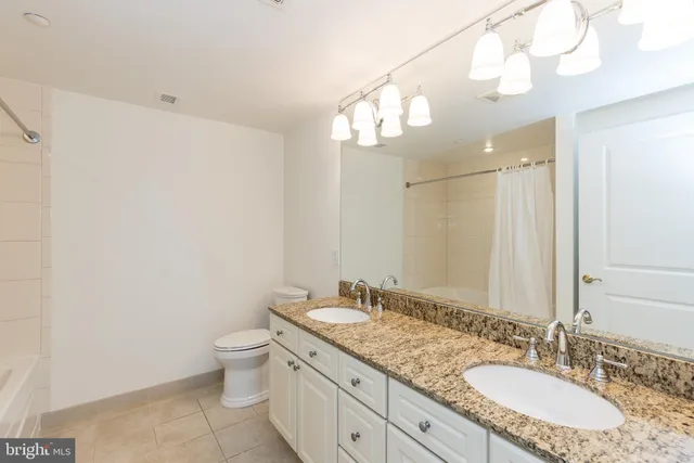 a bathroom with a granite countertop sink a toilet and a mirror