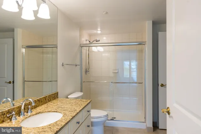 a bathroom with a granite countertop sink toilet and shower