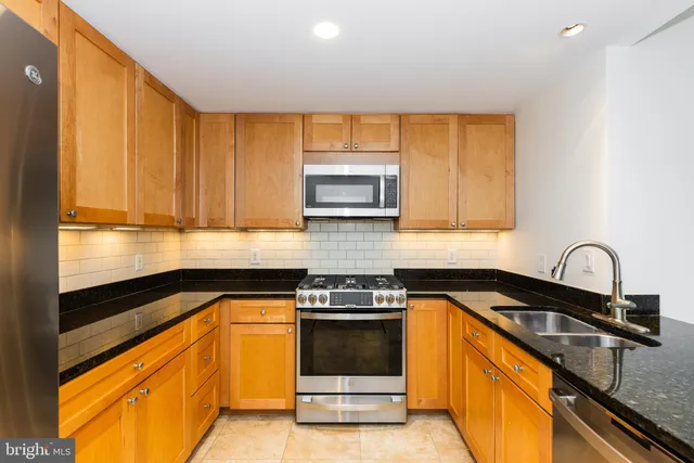 a kitchen with granite countertop a stove a sink and a microwave