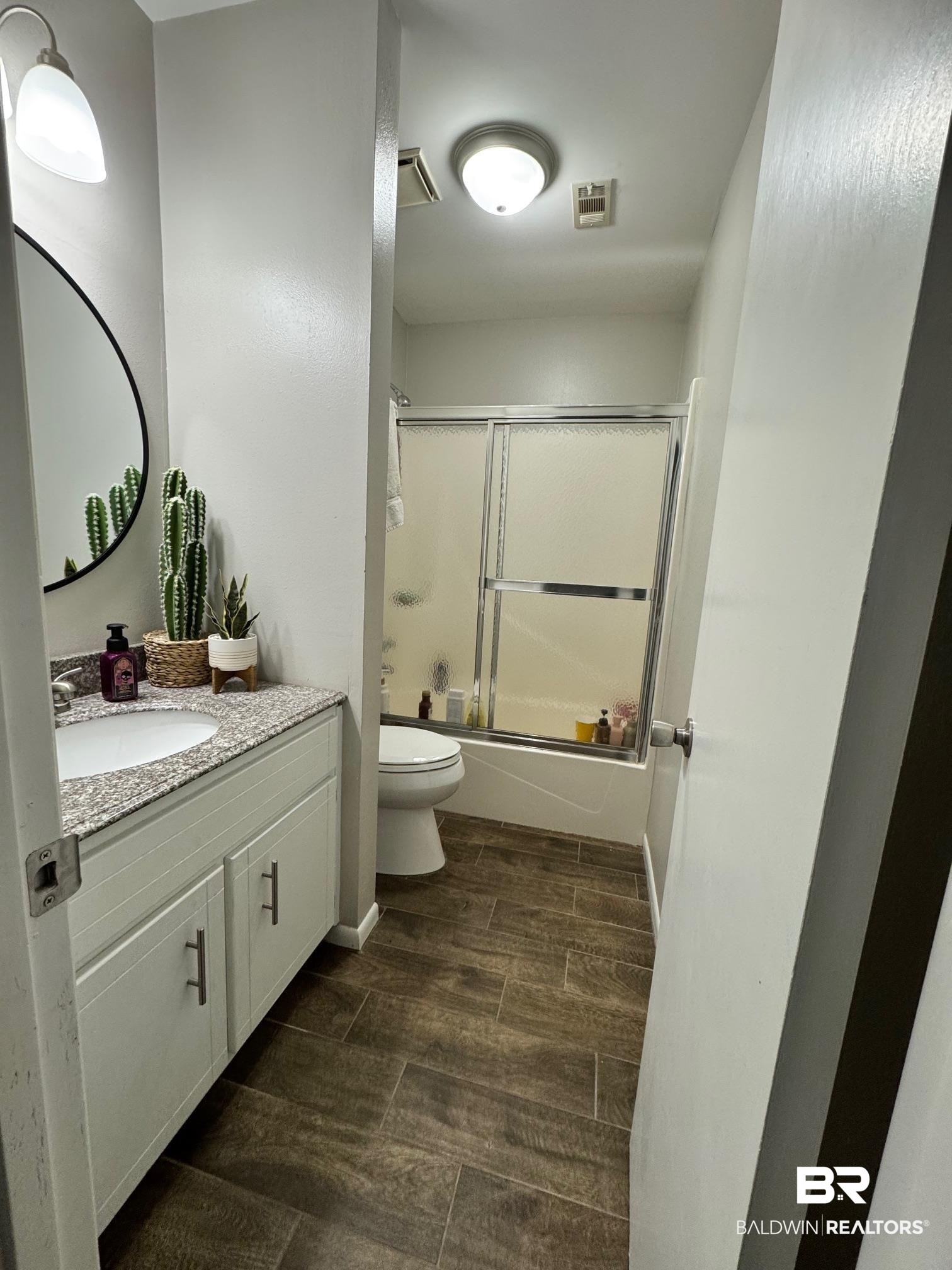 1434 Ridgewood Drive Lillian, AL 36549 - Photo 20 of 45 Full bathroom featuring shower / bath combination with glass door, vanity, and toilet