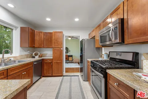 a kitchen with stainless steel appliances granite countertop a stove a sink dishwasher and a refrigerator