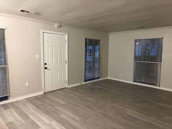 a view of an empty room with wooden floor and closet