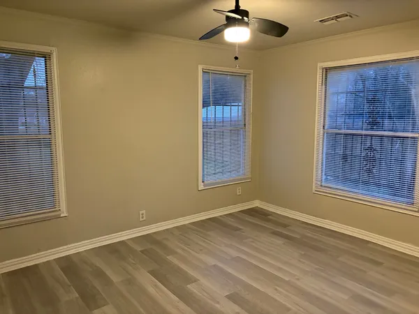 a view of an empty room with a window and chandelier fan