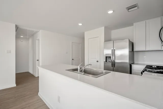 a kitchen with stainless steel appliances granite countertop a sink a refrigerator and a granite counter tops with wooden floors