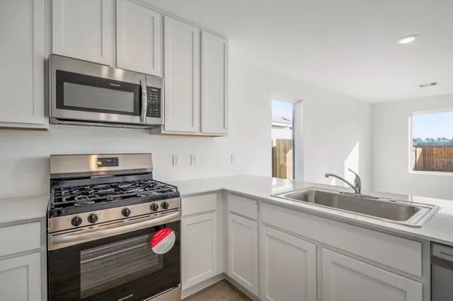 a kitchen with stainless steel appliances granite countertop white cabinets a microwave oven and a sink
