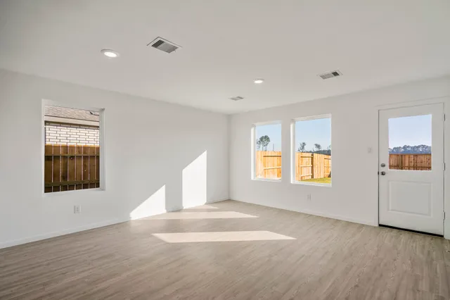 a view of an empty room with a window and wooden floor
