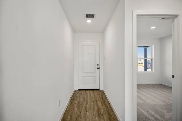 a view of a hallway with wooden floor and a bathroom