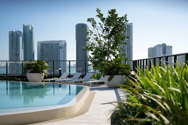 a view of a swimming pool with chairs and potted plants