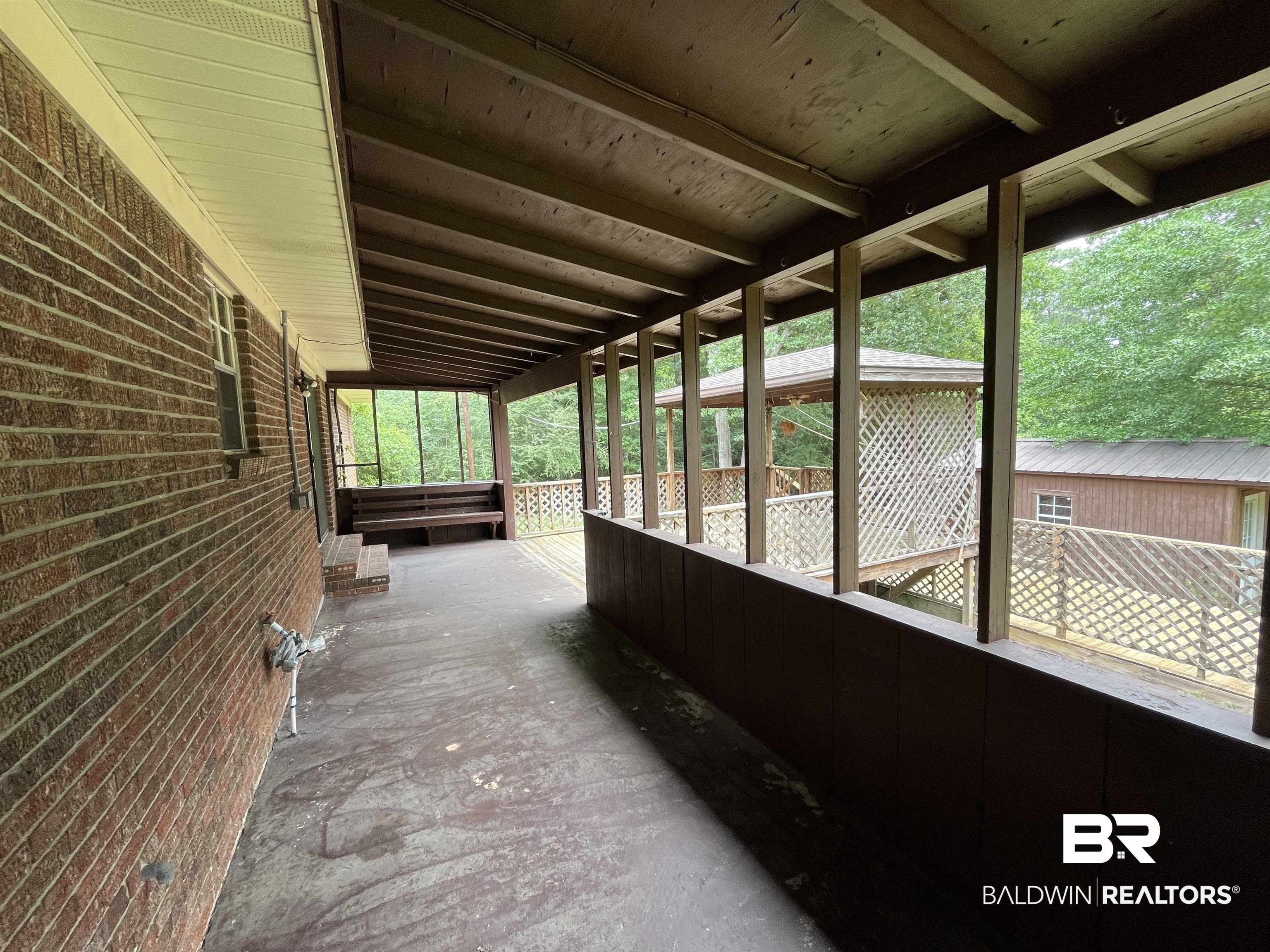 1905 Rockaway Creek Road Atmore, AL 36502 - Photo 16 of 23 Expansive outdoor covered patio featuring a brick exterior wall, exposed wood beam ceiling, and a screened enclosure