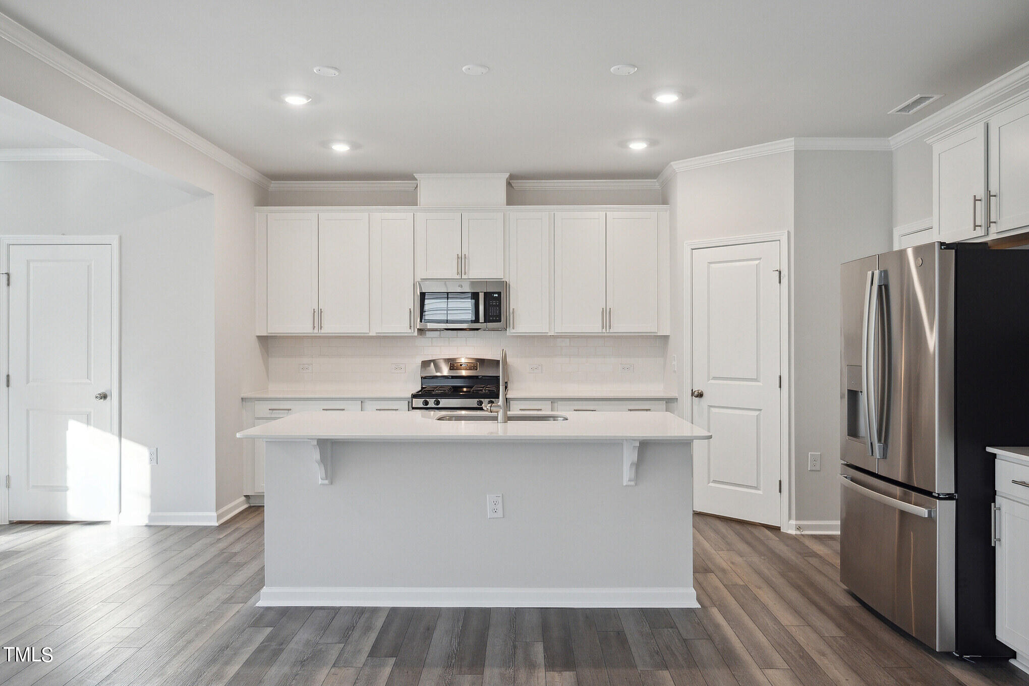 532 Hanover Shore Lane Raleigh, NC 27610 - Photo 9 of 31 a kitchen with stainless steel appliances a refrigerator stove a sink and white cabinets with wooden floor
