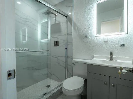 a bathroom with a shower sink vanity mirror and toilet