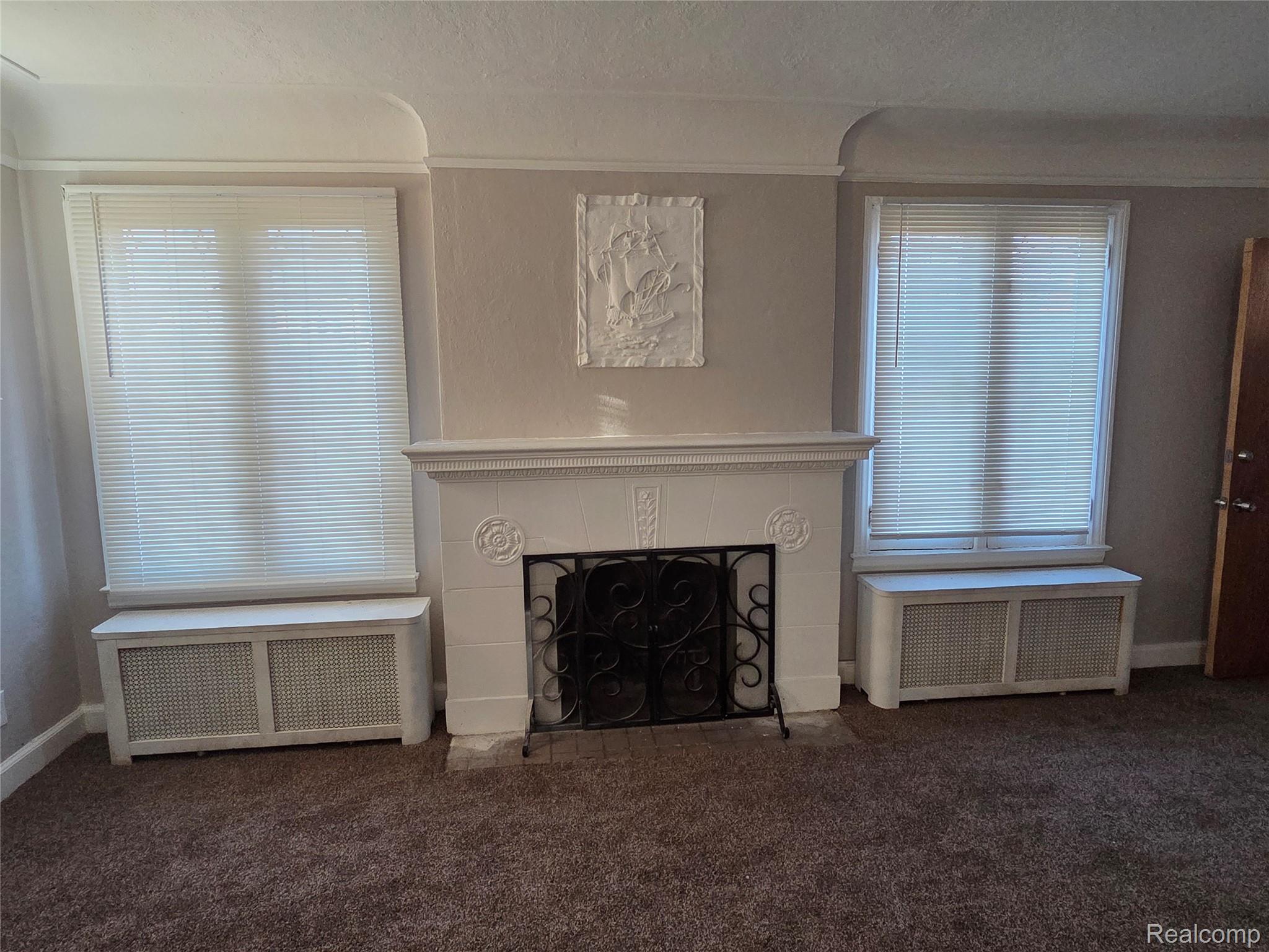 5274 Nottingham Road Detroit, MI 48224 - Photo 4 of 18 Unfurnished living room featuring radiator heating unit, a tiled fireplace, and dark colored carpet