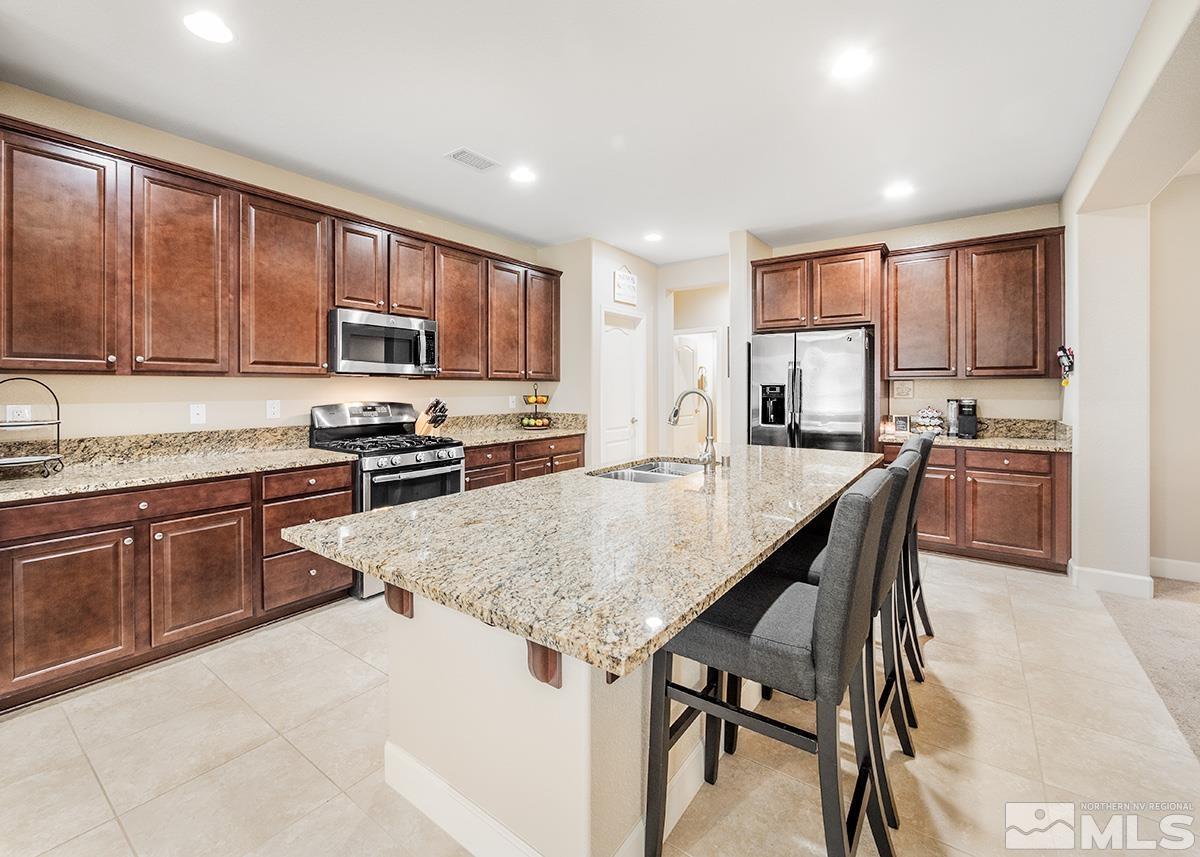 10250 Mott Drive Reno, NV 89521 - Photo 5 of 20 a kitchen with kitchen island granite countertop wooden cabinets a stove a sink a oven with dining table and chairs