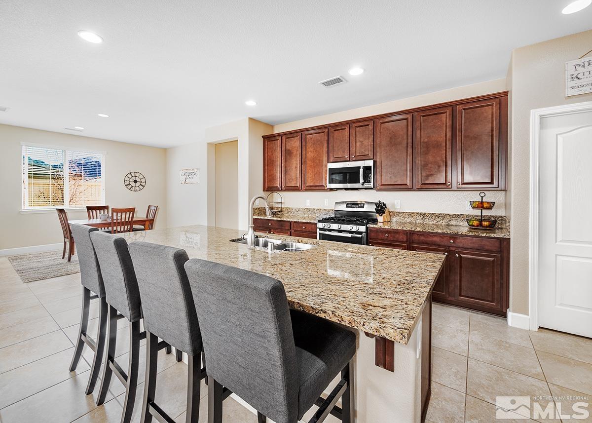 10250 Mott Drive Reno, NV 89521 - Photo 6 of 20 a kitchen with stainless steel appliances granite countertop a stove a sink a microwave a dining table and chairs