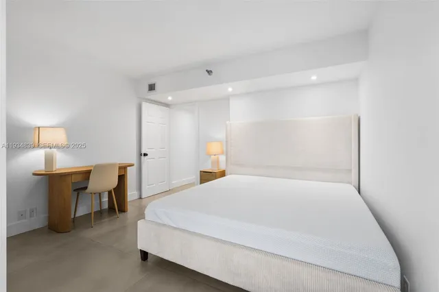 a large bed sitting in a room next to a lamp with table and a window