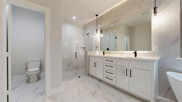 a spacious bathroom with a double vanity sink a toilet and a shower