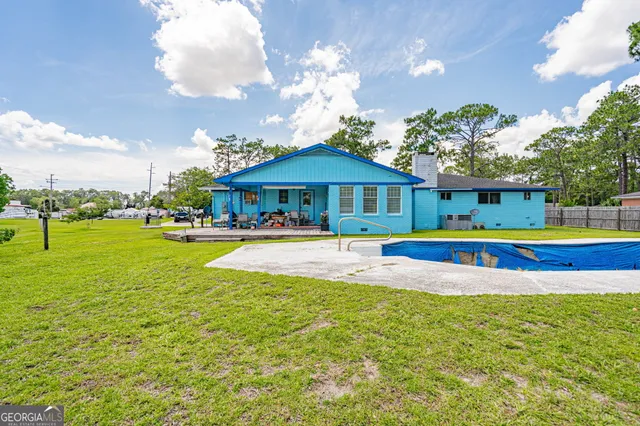a view of swimming pool with umbrella and trees in the background