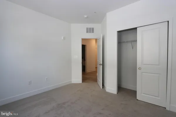 a view of an empty room with closet and wooden door