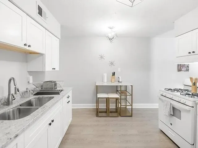 a kitchen with stainless steel appliances a white stove top oven and white cabinets