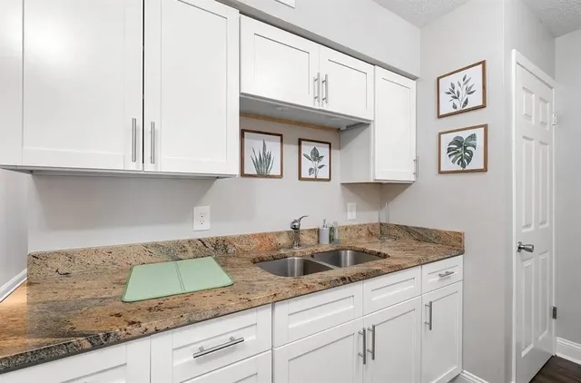 a kitchen with granite countertop white cabinets and a sink