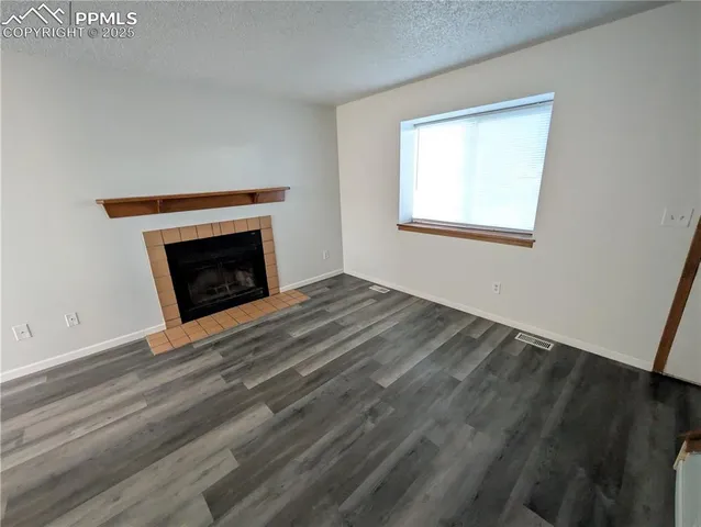 an empty room with wooden floor fireplace and windows