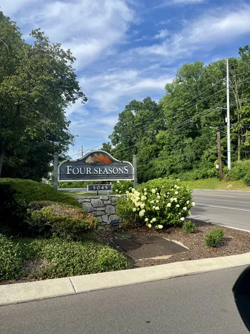 a sign board with a house in the background