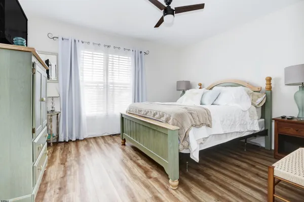 a bedroom with a bed a mirror on the dresser and a window