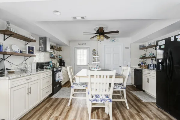 a kitchen with stainless steel appliances kitchen island granite countertop a dining table chairs and white cabinets