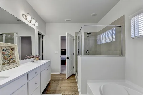 a spacious bathroom with a double vanity sink a large mirror and a bathtub