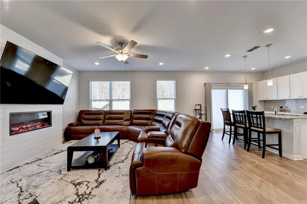 a living room with furniture a ceiling fan and a flat screen tv