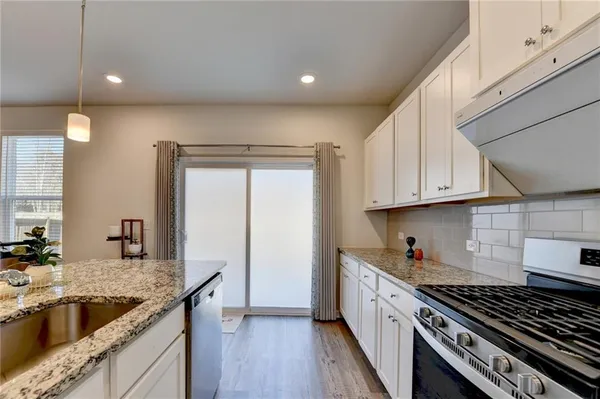a kitchen with granite countertop a sink stove and cabinets