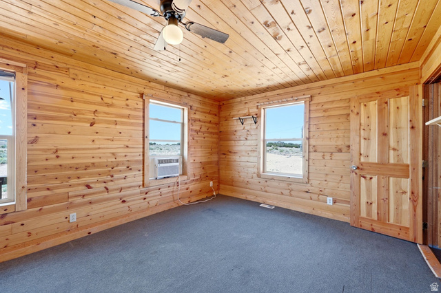 10937 South County Road, Unit 29 Duchesne, UT 84021 - Photo 14 of 41 Interior space featuring wood-paneled walls and ceiling, two windows, a ceiling fan, and a paneled wood door