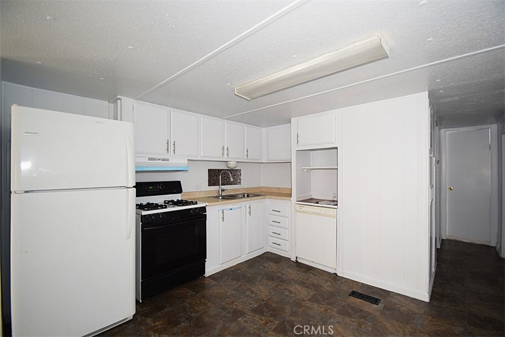 6426 Valley View Street, Unit 39 Joshua Tree, CA 92252 - Photo 6 of 11 a kitchen with a refrigerator a stove top oven and white kitchen island