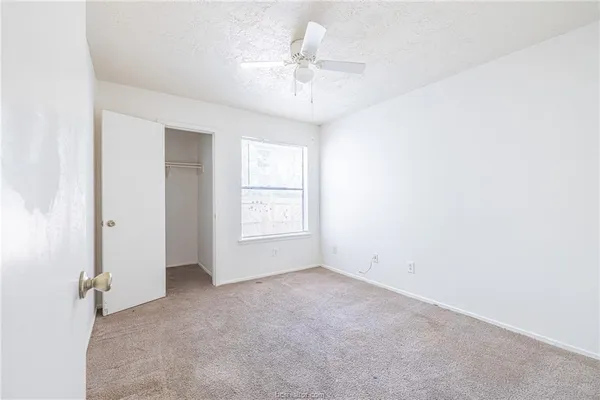 an empty room with a ceiling fan and window