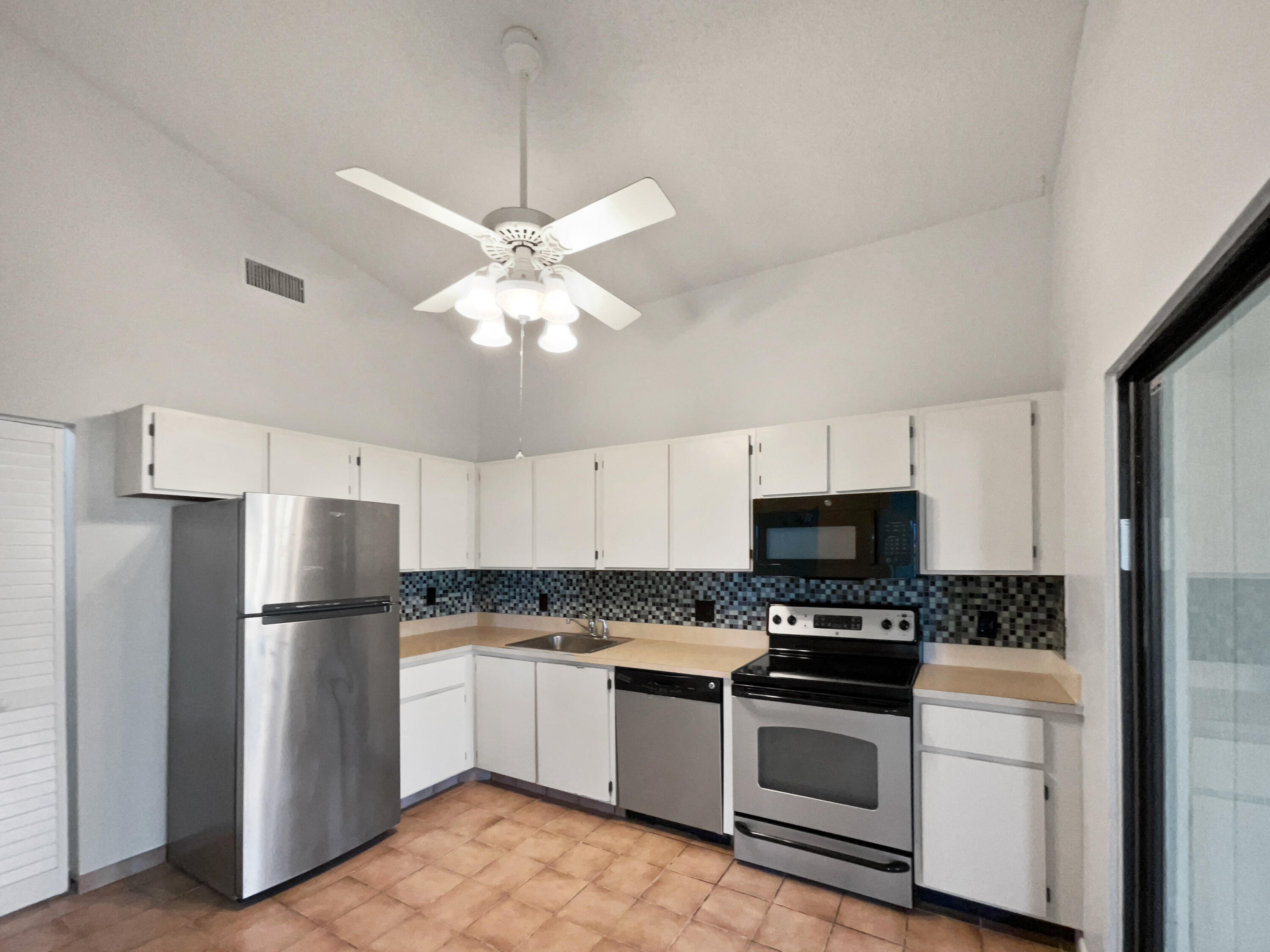 4249 Willow Pond Circle West Palm Beach, FL 33417 - Photo 16 of 30 a kitchen with stainless steel appliances a refrigerator sink and white cabinets