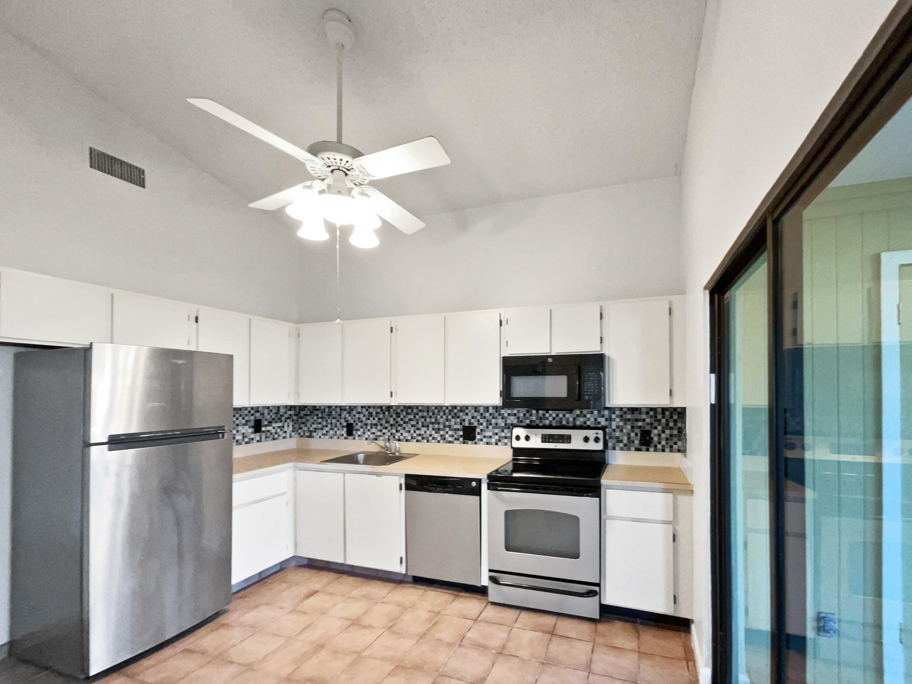 4249 Willow Pond Circle West Palm Beach, FL 33417 - Photo 17 of 30 a kitchen with a refrigerator a stove top oven a cabinetry and stainless steel appliances