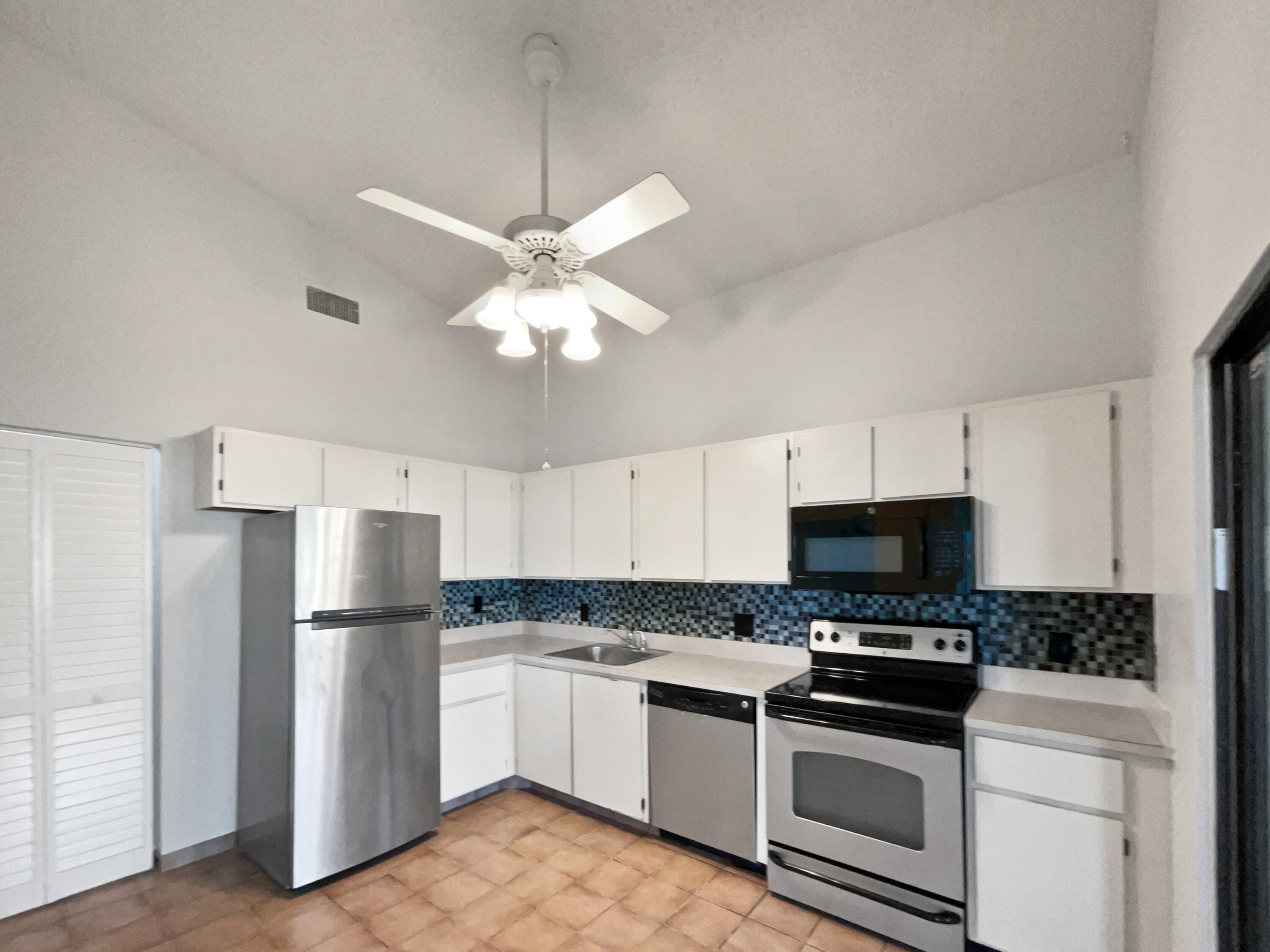 4249 Willow Pond Circle West Palm Beach, FL 33417 - Photo 6 of 30 a kitchen with stainless steel appliances a refrigerator a stove sink and white cabinets
