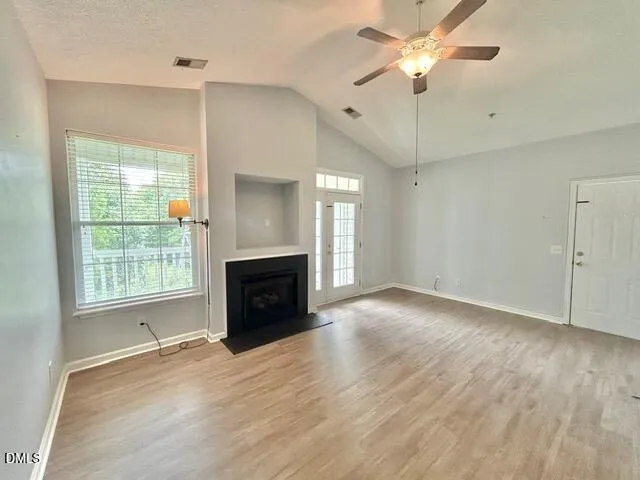 a view of an empty room with a fireplace and a window