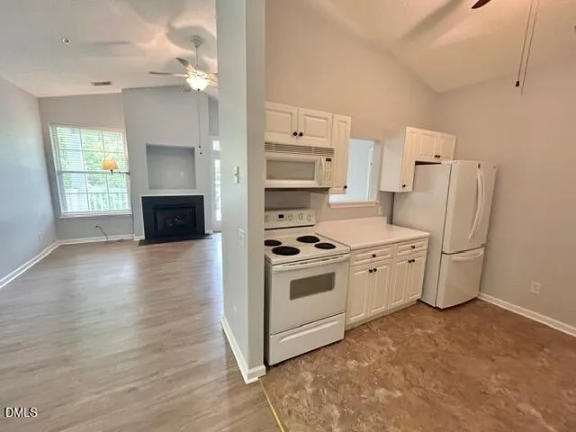 a kitchen with stainless steel appliances a stove top oven a refrigerator a sink and dishwasher with white cabinets