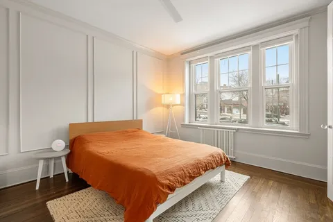 a bedroom with a bed a chair and next to a window