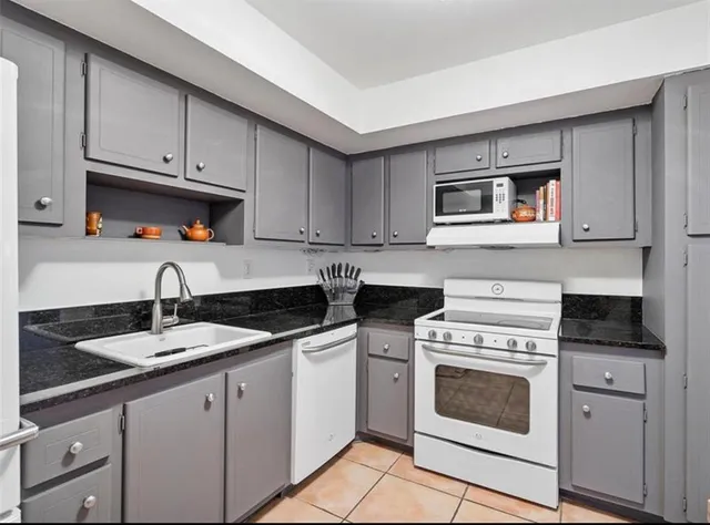 a kitchen with granite countertop a stove sink and cabinets