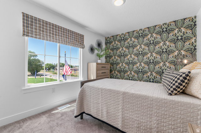 1418 West 2350th South, Unit 15 Perry, UT 84302 - Photo 17 of 22 Bright room featuring a large window, patterned accent wall, recessed ceiling light, and carpeted flooring